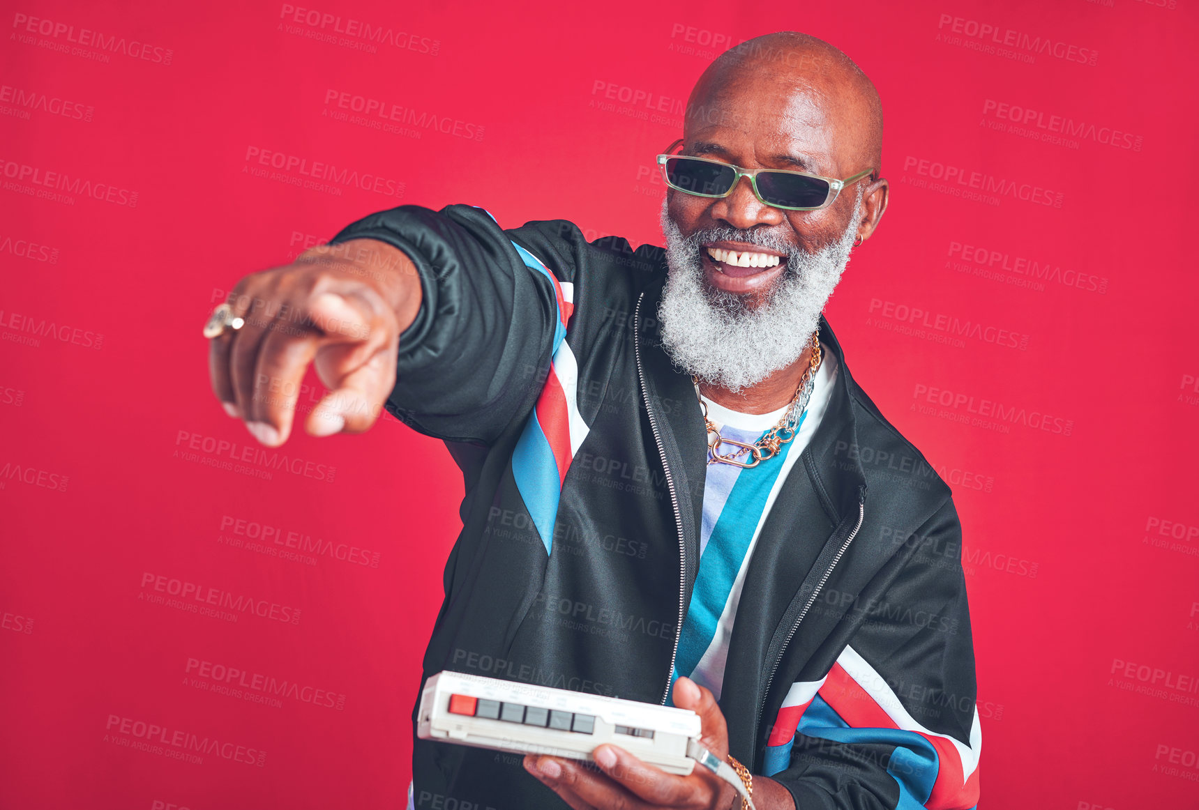 Buy stock photo Studio shot of a mature man holding a cassette player against a red background