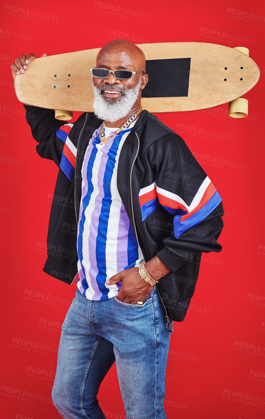Buy stock photo Shot of a mature man holding a skateboard against a red background
