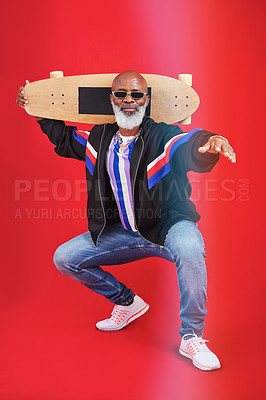 Buy stock photo Shot of a mature man holding a skateboard against a red background
