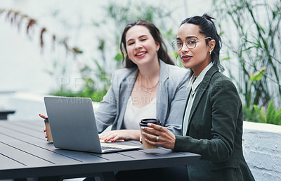 Buy stock photo Shot of two young businesswomen using a laptop during a meeting at a coffee shop