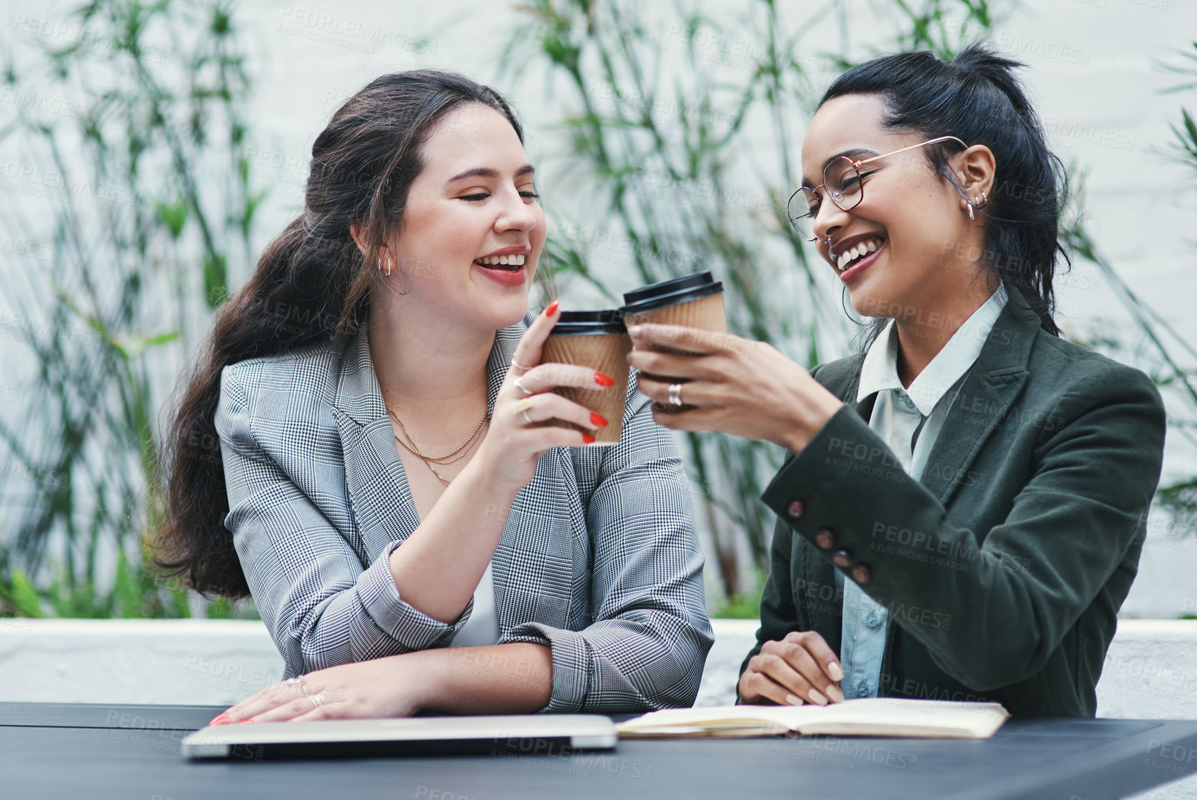 Buy stock photo Shot of two young businesswomen toasting with coffee during a business meeting