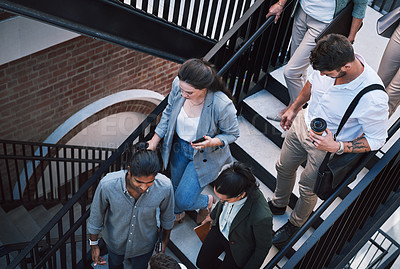 Buy stock photo Shot of a group of businesspeople walking up the stairs in a modern workplace