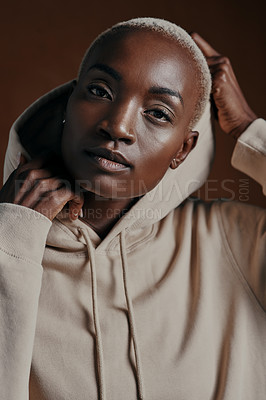 Buy stock photo Studio portrait of an attractive young woman wearing a hoodie and posing against a brown background