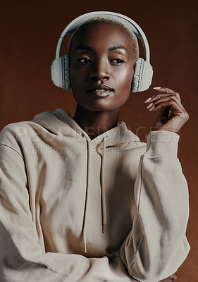 Buy stock photo Studio shot of an attractive young woman wearing headphones and posing against a brown background
