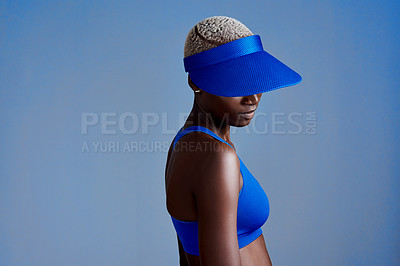 Buy stock photo Studio shot of a sporty young woman wearing a visor while posing against a blue background