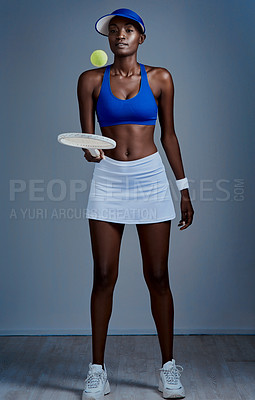 Buy stock photo Studio shot of a sporty young woman posing with tennis equipment against a grey background