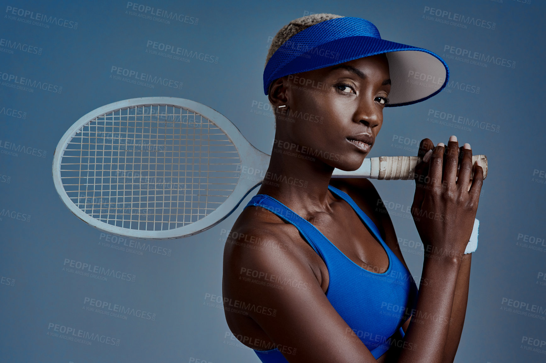 Buy stock photo Sports, portrait and black woman with tennis racket in studio for competition, training and practice. African person, serious and visor with equipment for fitness, workout and game by blue background