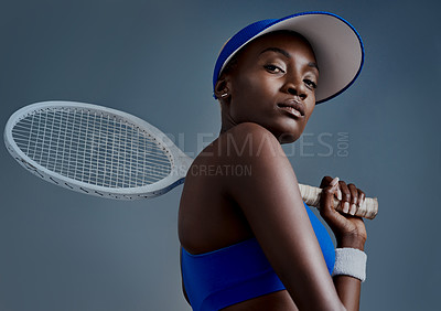 Buy stock photo Studio shot of a sporty young woman posing with a tennis racket against a grey background