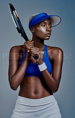 Buy stock photo Studio shot of a sporty young woman posing with a tennis racket against a grey background