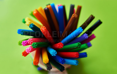 Buy stock photo Studio shot of different coloured felt tip pens in a pen holder against a green background