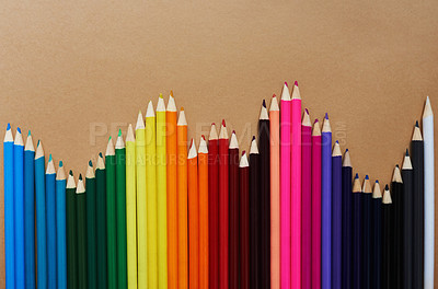 Buy stock photo Studio shot of different coloured pencils against a brown background