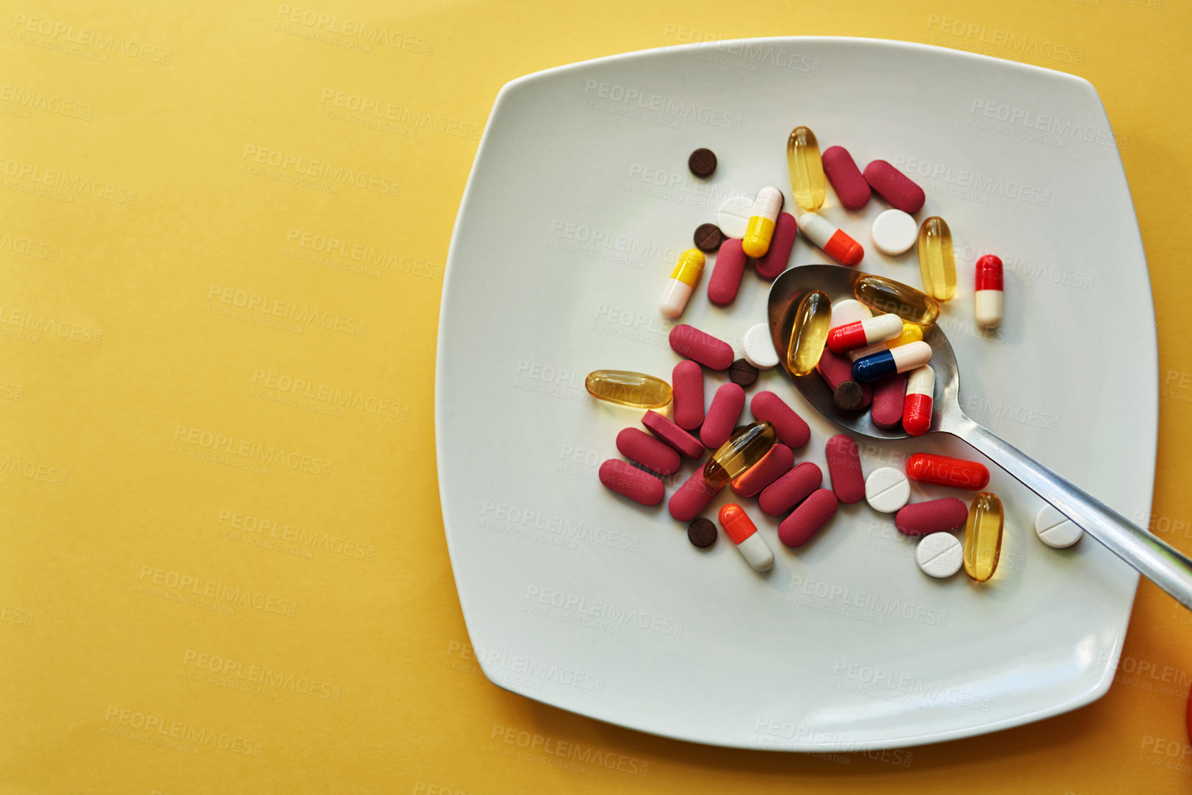 Buy stock photo Studio shot of medication served on a plate with a spoon against a yellow background