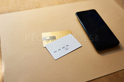Buy stock photo Shot of two credit cards and a smartphone on a desk