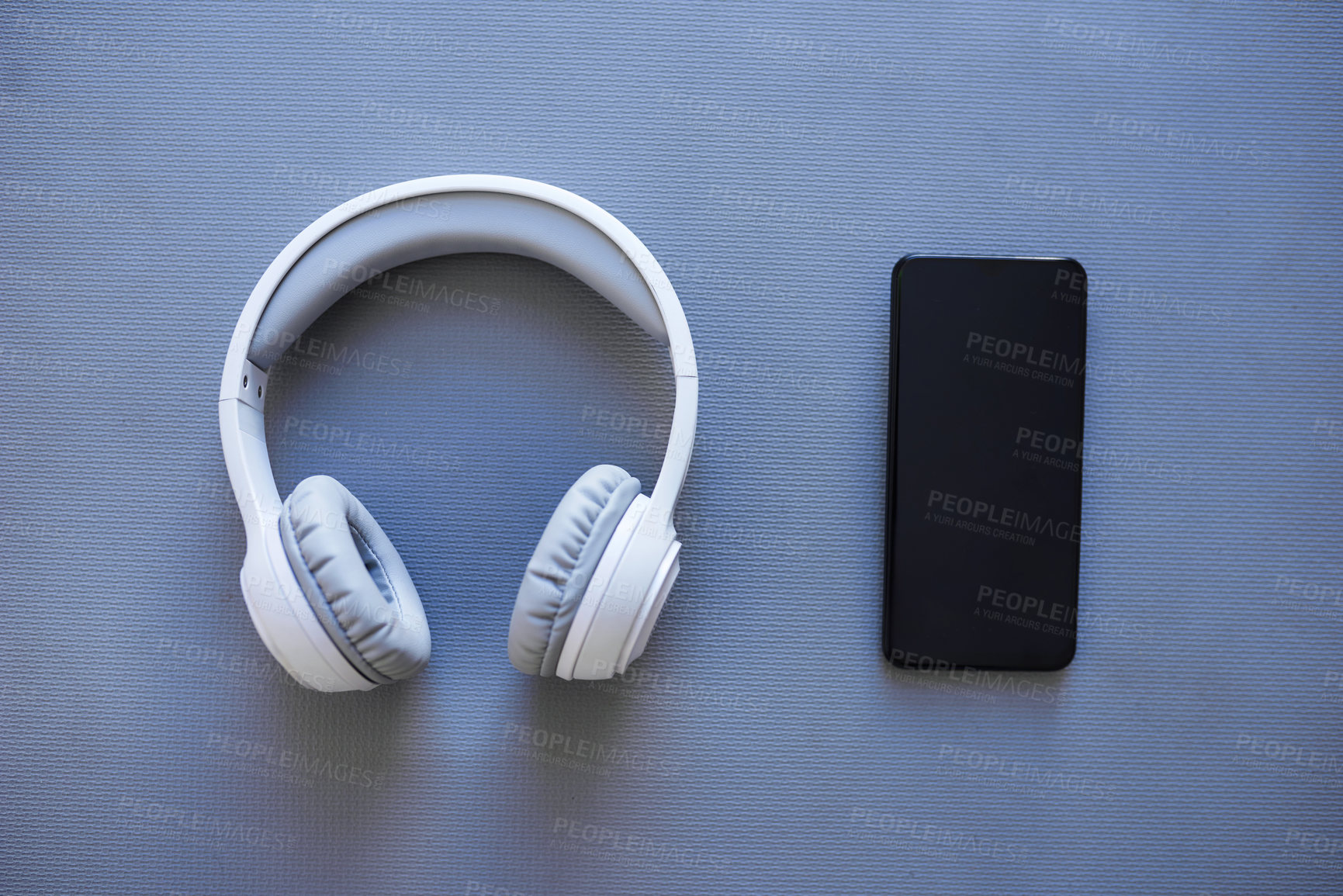 Buy stock photo Phone, headphones and streaming music in studio, subscription and sound on gray background. Mobile, internet connection and online for podcast entertainment, album track and website for song playlist