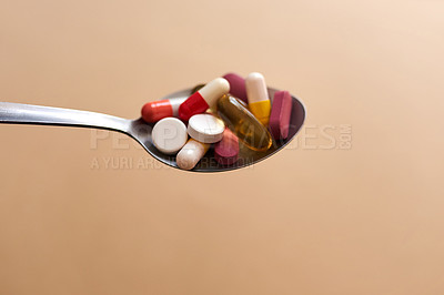 Buy stock photo Studio shot of medication served in a spoon against a brown background