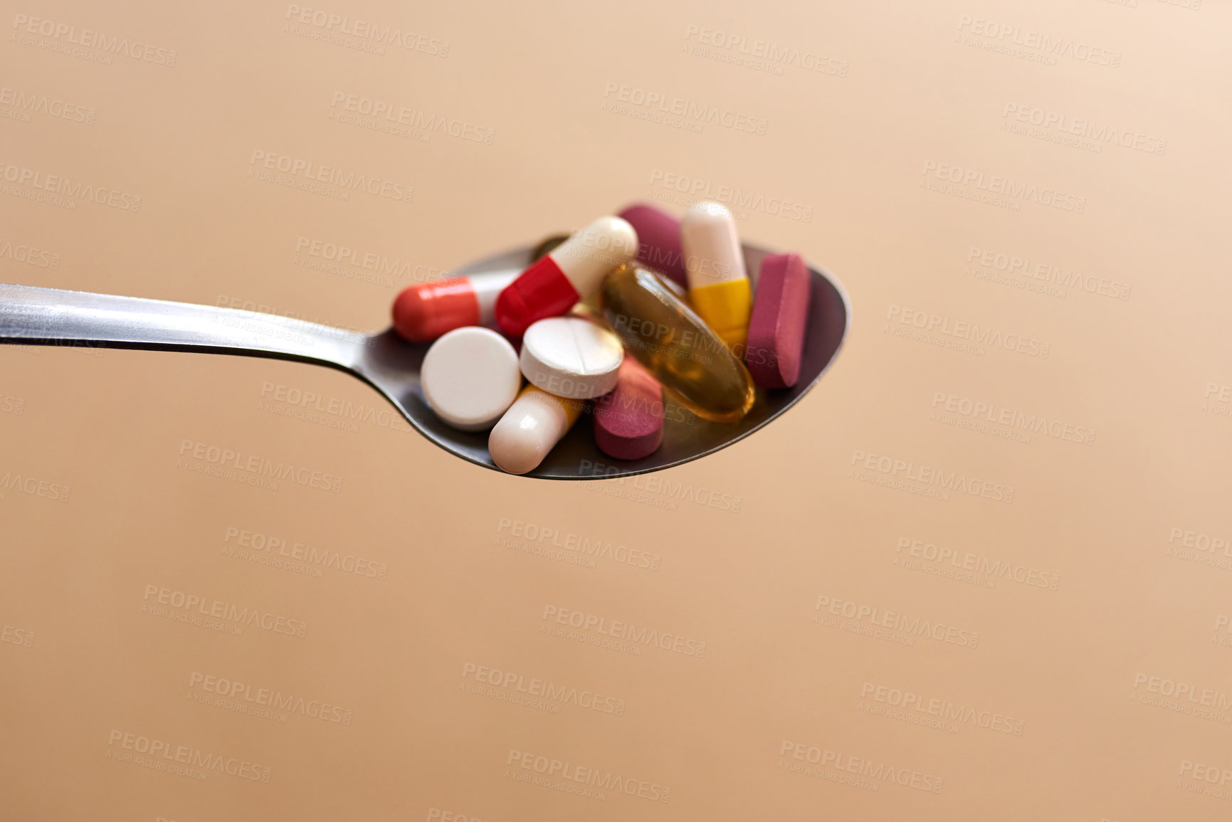 Buy stock photo Studio shot of medication served in a spoon against a brown background