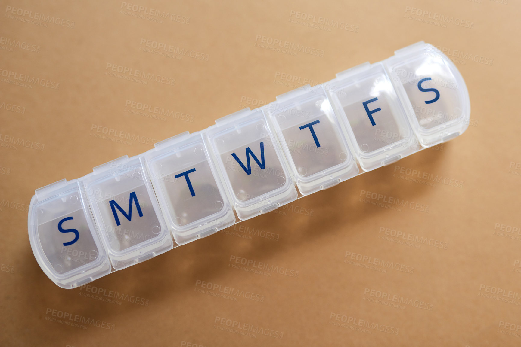 Buy stock photo Studio shot of an empty medicine organizer against a brown background