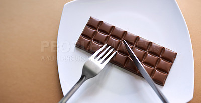 Buy stock photo Studio shot of chocolate served on a plate with a fork and knife against a brown background