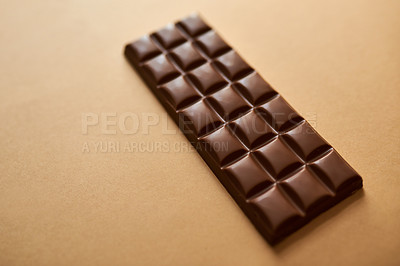 Buy stock photo Studio shot of a slab of chocolate against a brown background