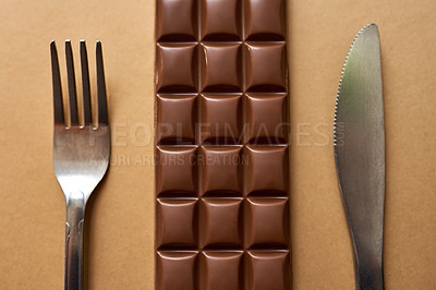 Buy stock photo Studio shot of chocolate served with a fork and knife against a brown background