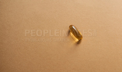 Buy stock photo Studio shot of a single gel capsule against a brown background