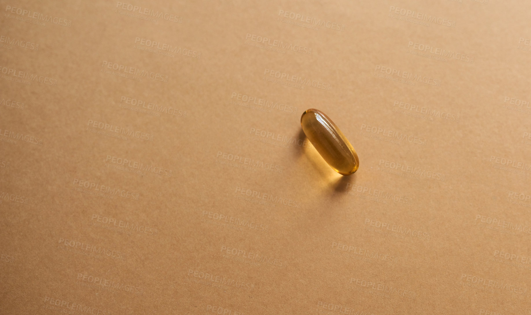 Buy stock photo Studio shot of a single gel capsule against a brown background