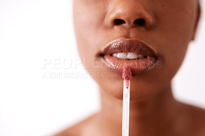 Buy stock photo Studio shot of an unrecognizable woman applying gloss to her lips