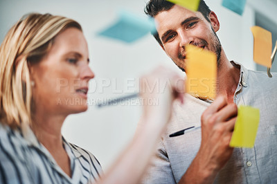 Buy stock photo Cropped shot of two business colleagues brainstorming on a glass wipe board in their office