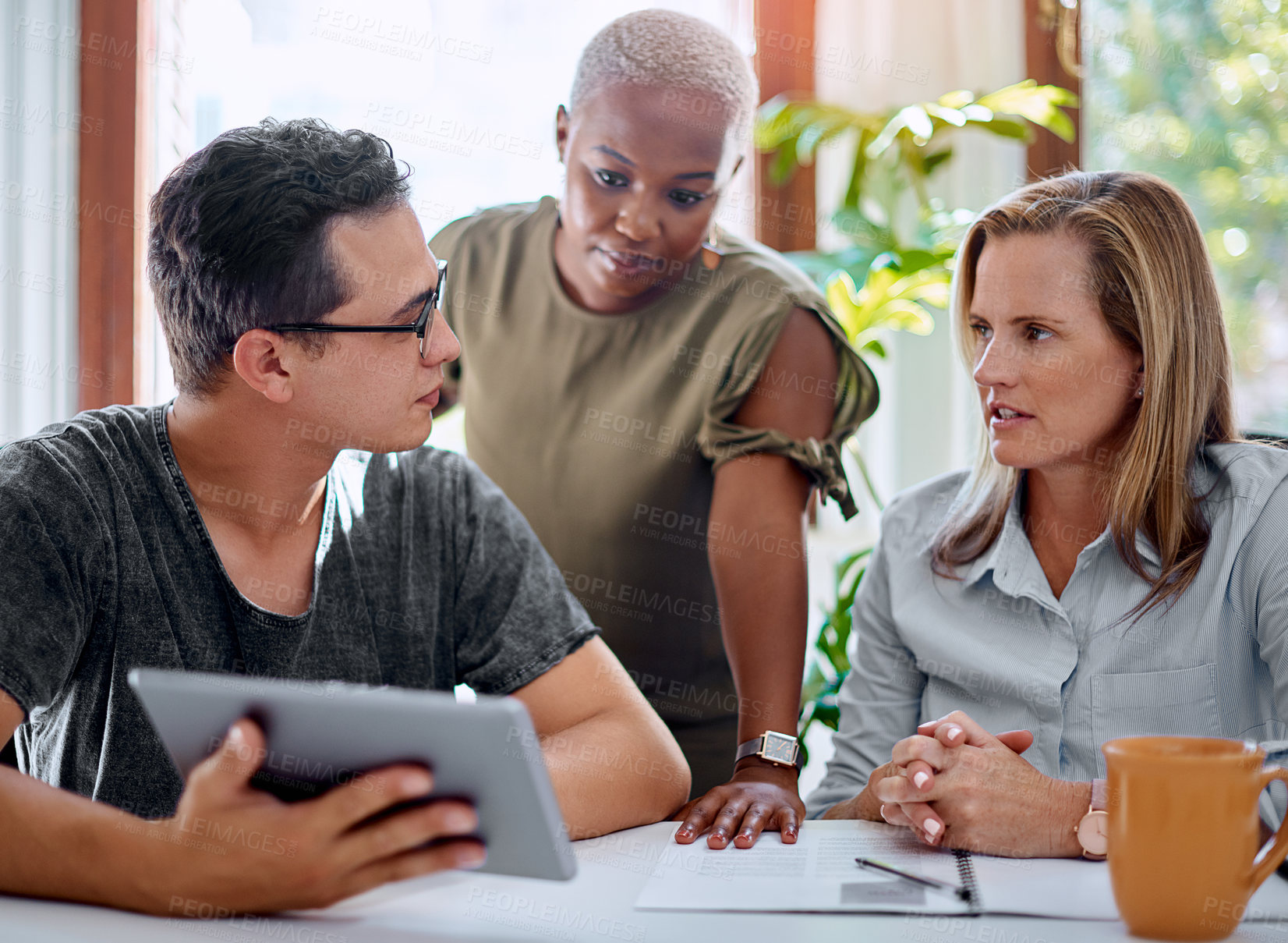 Buy stock photo Shot of a group of businesspeople working together on a digital tablet in an office