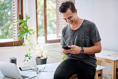 Buy stock photo Shot of a young businessman using a cellphone in an office