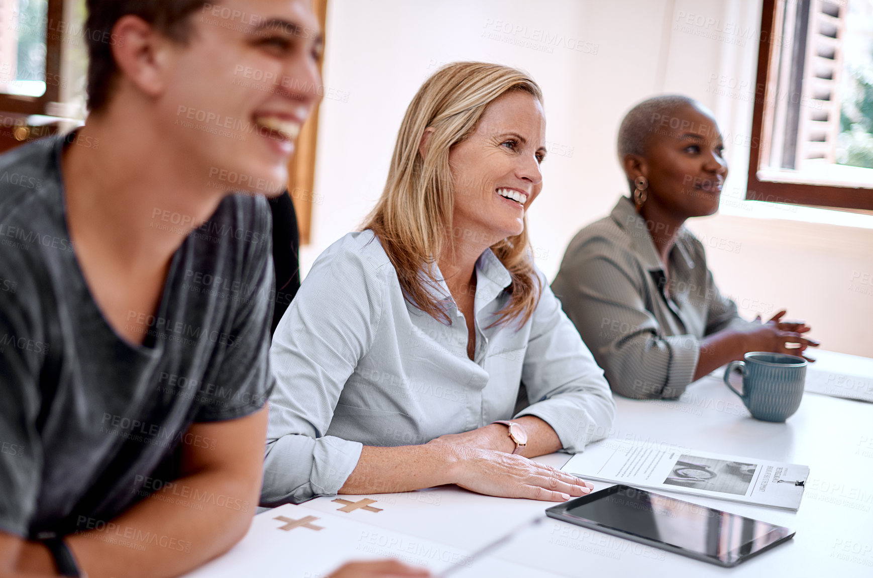 Buy stock photo Shot of a mature businesswoman sitting alongside her colleagues during a presentation in an office