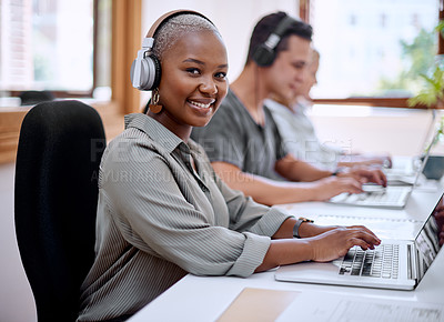 Buy stock photo Portrait of a young businesswoman wearing headphones while working on a laptop in an office