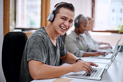 Buy stock photo Portrait of a young businessman wearing headphones while working on a laptop in an office