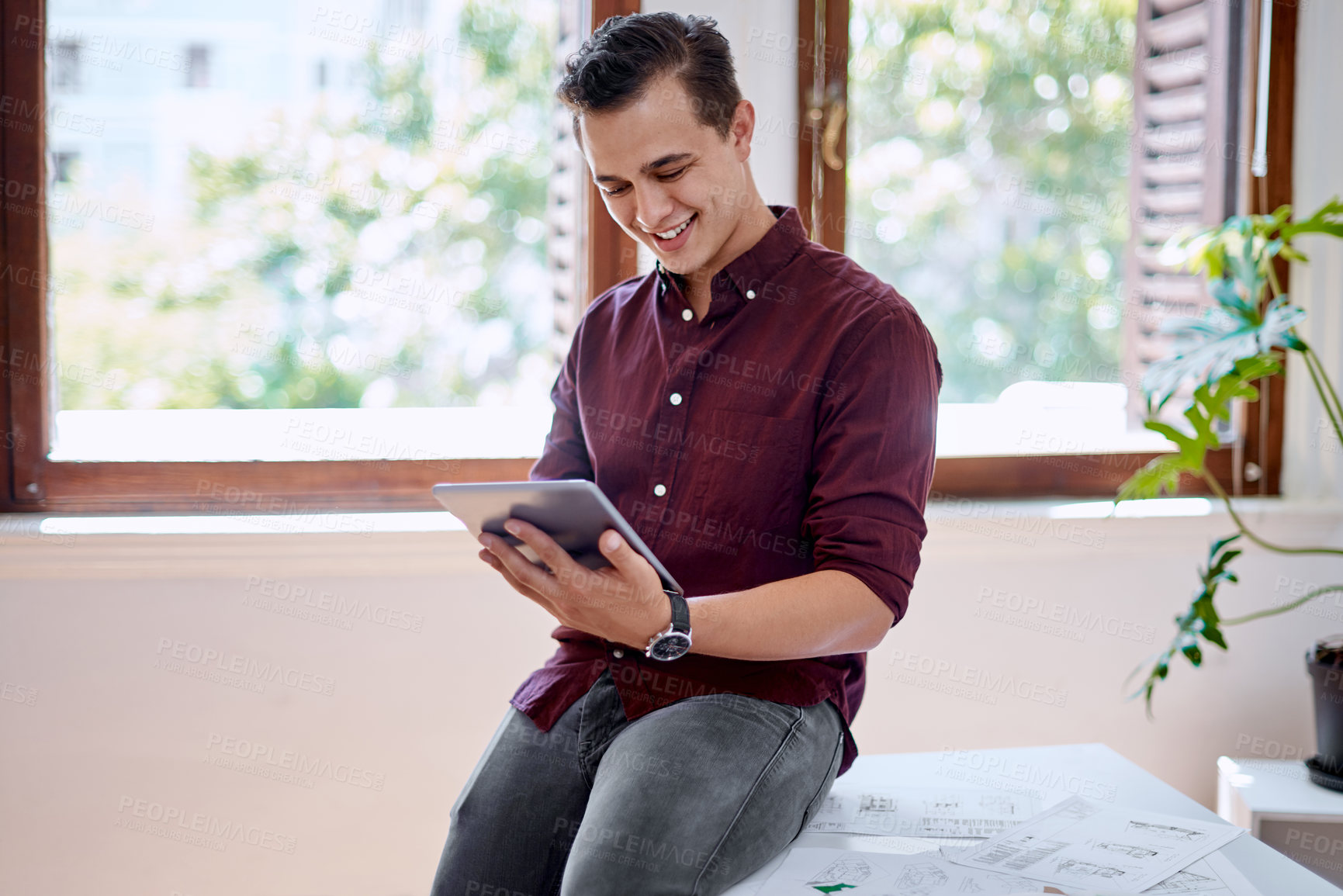 Buy stock photo Shot of a young businessman using a digital tablet in an office