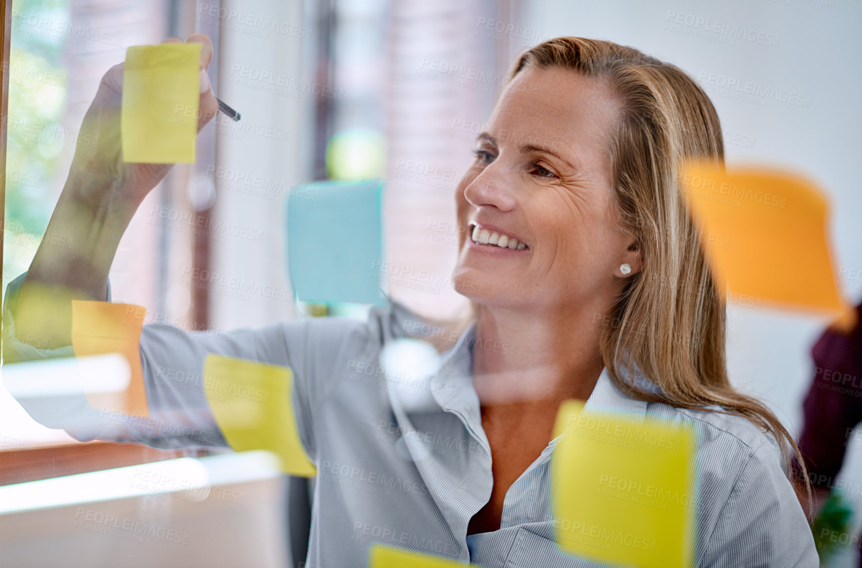 Buy stock photo Shot of a mature businesswoman writing notes on a glass wall in an office