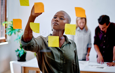Buy stock photo Shot of a young businesswoman writing notes on a glass wall in an office