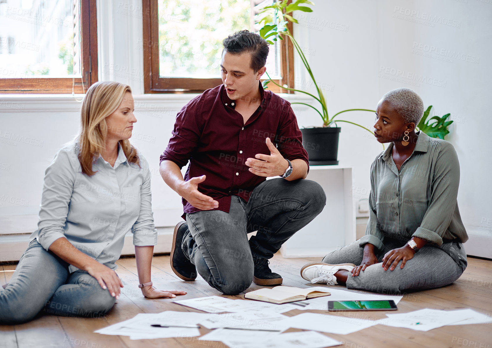 Buy stock photo Shot of a group of businesspeople brainstorming with notes on a floor in an office