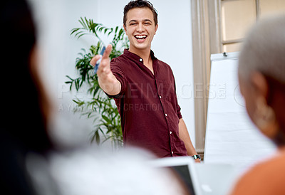 Buy stock photo Shot of a young businessman using a whiteboard while giving a presentation to his colleagues in an office