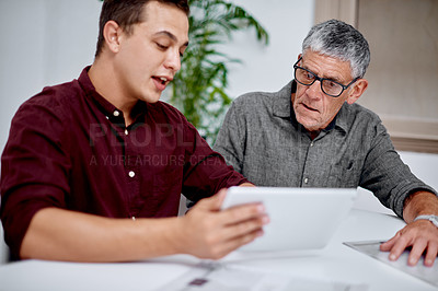 Buy stock photo Shot of two businessmen working together on a digital tablet in an office
