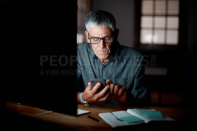 Buy stock photo Shot of a senior businessman using a cellphone in an office at night