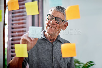 Buy stock photo Shot of a senior businessman brainstorming with notes on a glass wall in an office