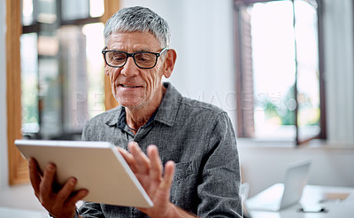 Buy stock photo Shot of a senior businessman using a digital tablet in an office