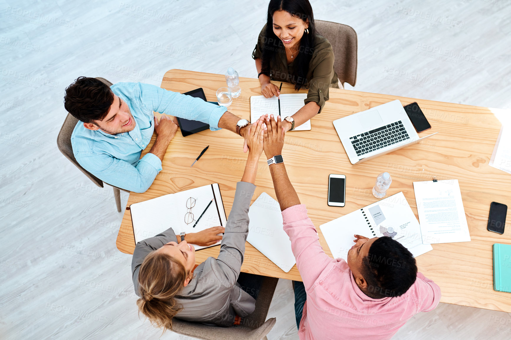 Buy stock photo High angle shot of a group of businesspeople giving each other a high five while working in an office