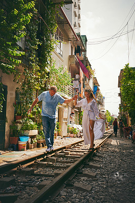 Buy stock photo Shot of a happy couple sharing a romantic moment on the train tracks in the streets of Vietnam