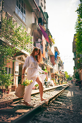 Buy stock photo Travel, woman and walking on railway with flowers for holiday adventure, vacation experience and confidence. Tourist, person and happy with floral basket on train track in Vietnam for sightseeing