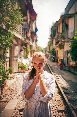 Buy stock photo Shot of a young woman walking on train tracks through the streets of Vietnam