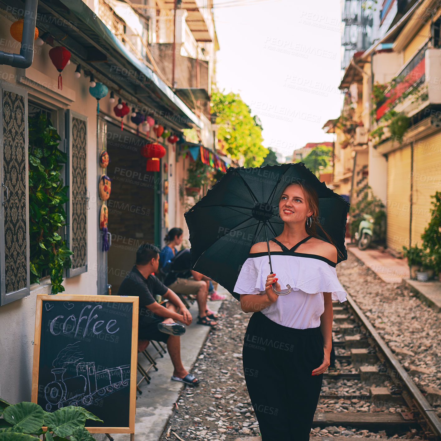 Buy stock photo Shot of a young woman holding an umbrella while exploring a foreign city on a sunny day