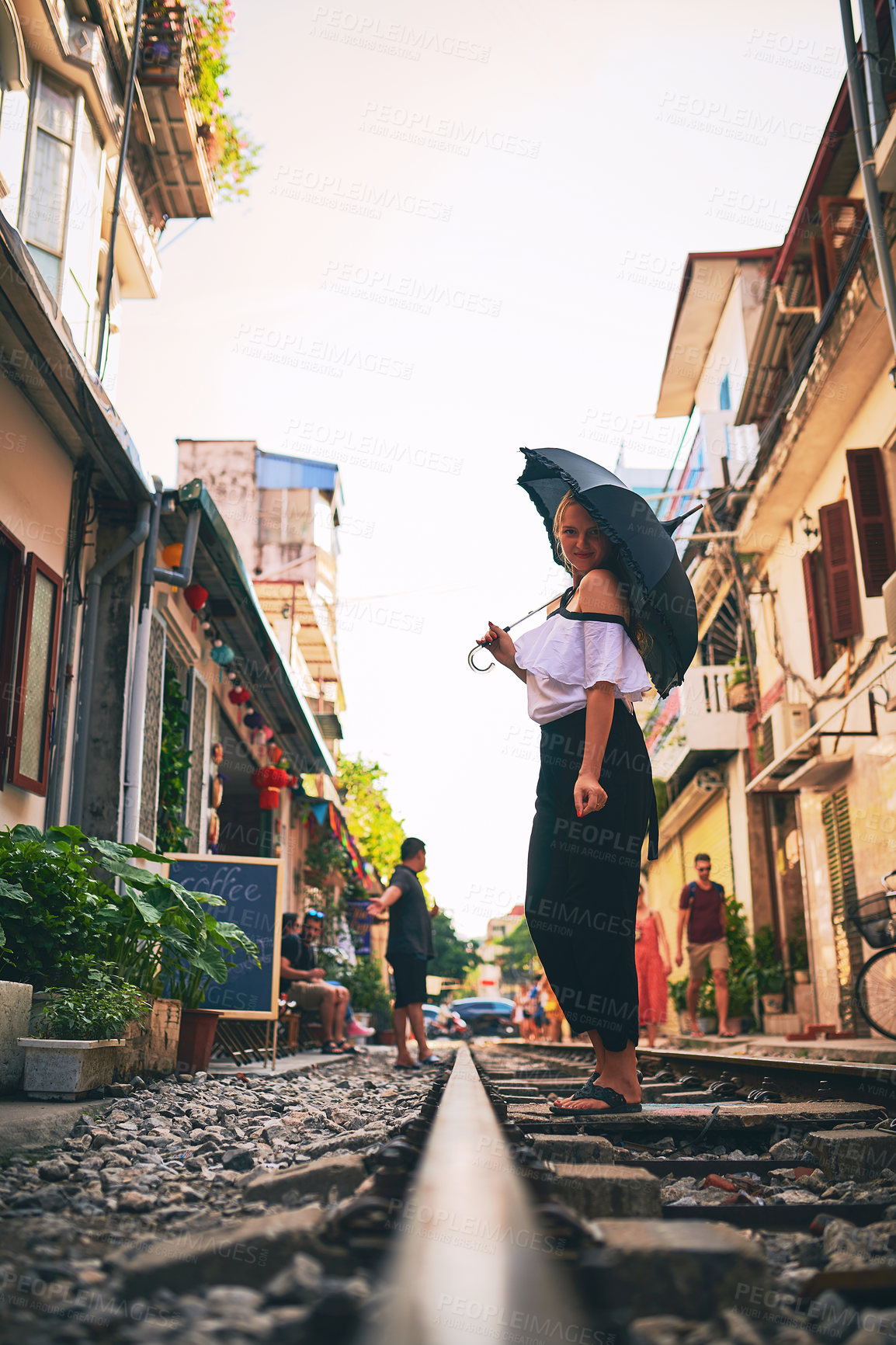 Buy stock photo Shot of a young woman holding an umbrella while exploring a foreign city on a sunny day