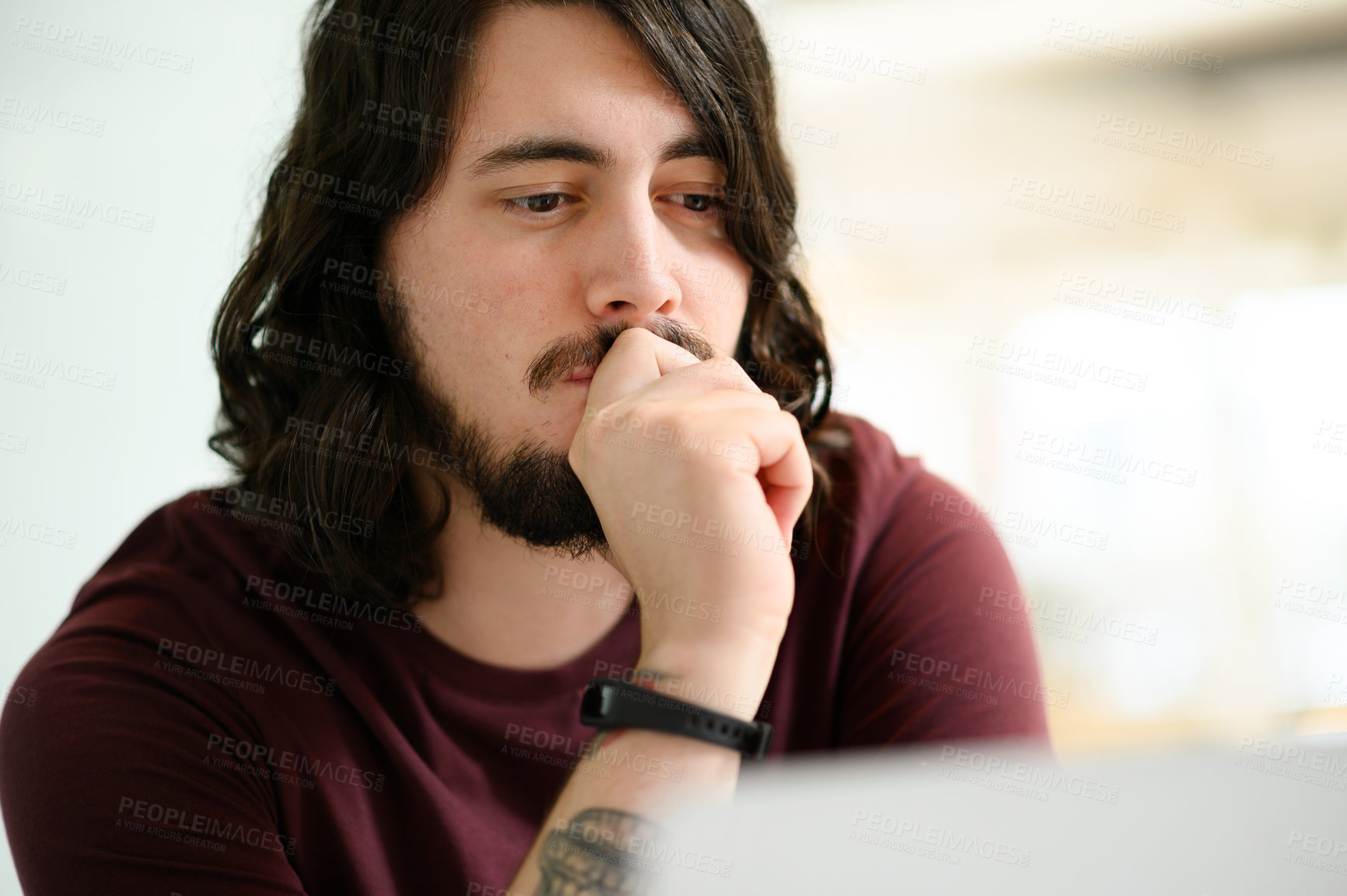 Buy stock photo Shot of a young businessman looking thoughtful while working in an office