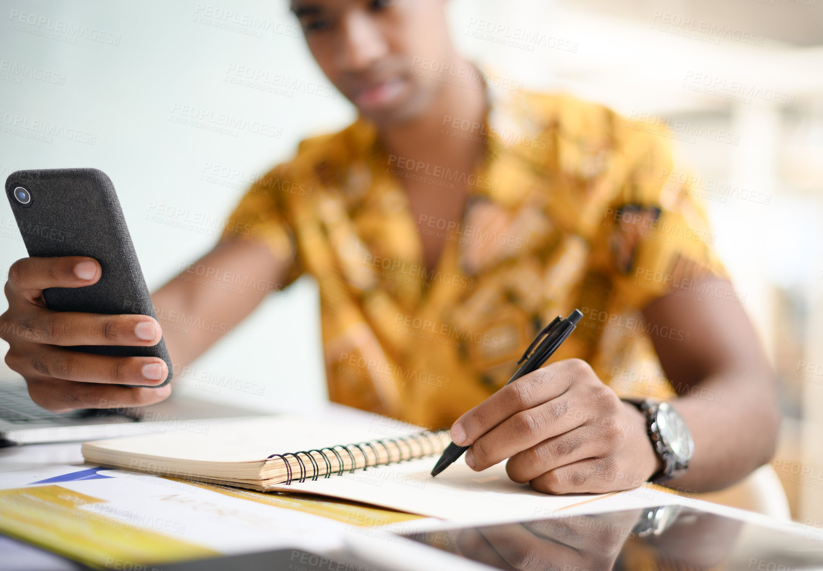 Buy stock photo Closeup shot of an unrecognisable businessman writing notes while using a cellphone in an office